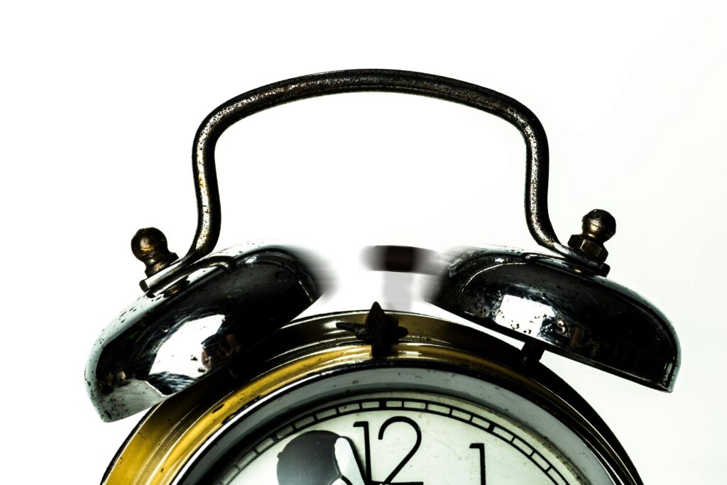 Close-up of a classic vintage alarm clock with ringing bells on a white background.